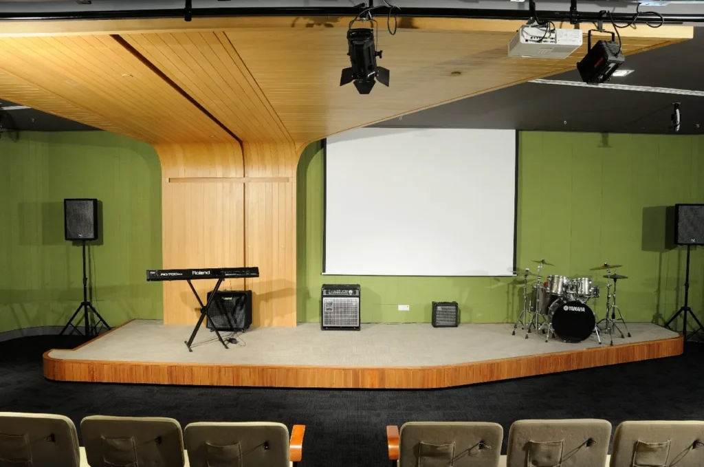 Theatrette stage with a keyboard, drum kit and projector screen