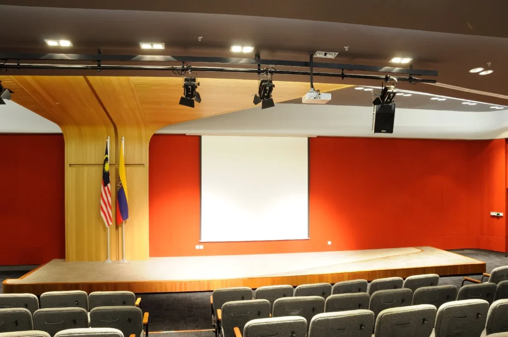 Theatrette stage with flags and a projector screen against red walls