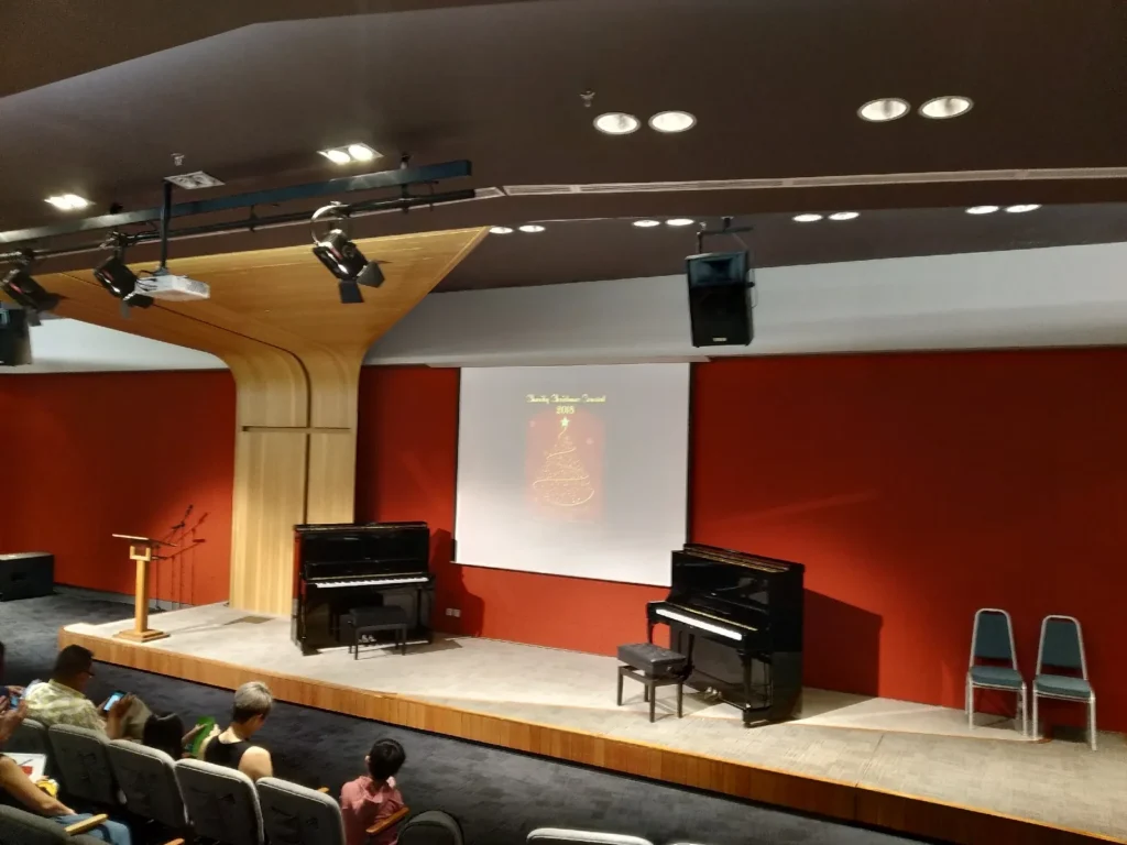 Theatrette stage with two upright pianos and a Christmas concert screen